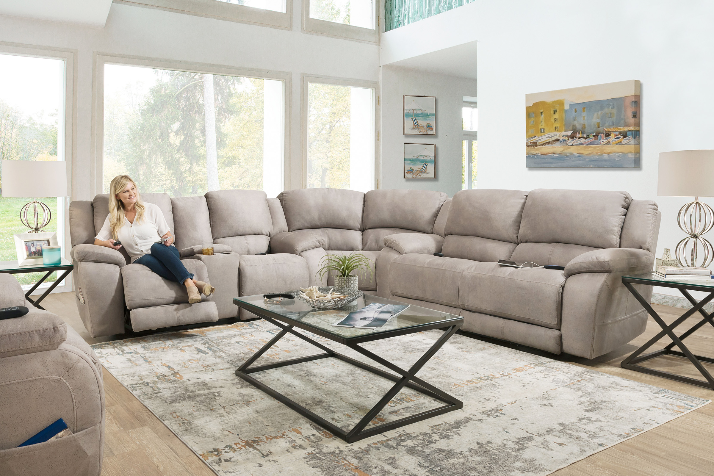 A lady sits in a long taupe sectional with the footrest raised.