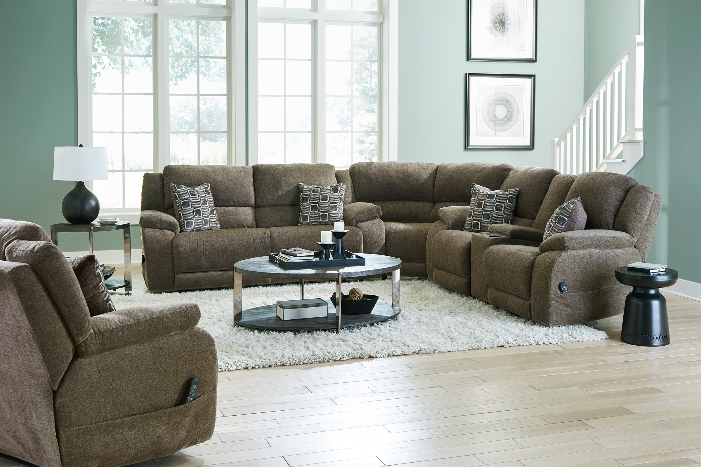 A large brown upholstered sectional sits in a living room on top of a white shag rug. 